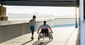 mujer corriendo con una mujer en silla de ruedas